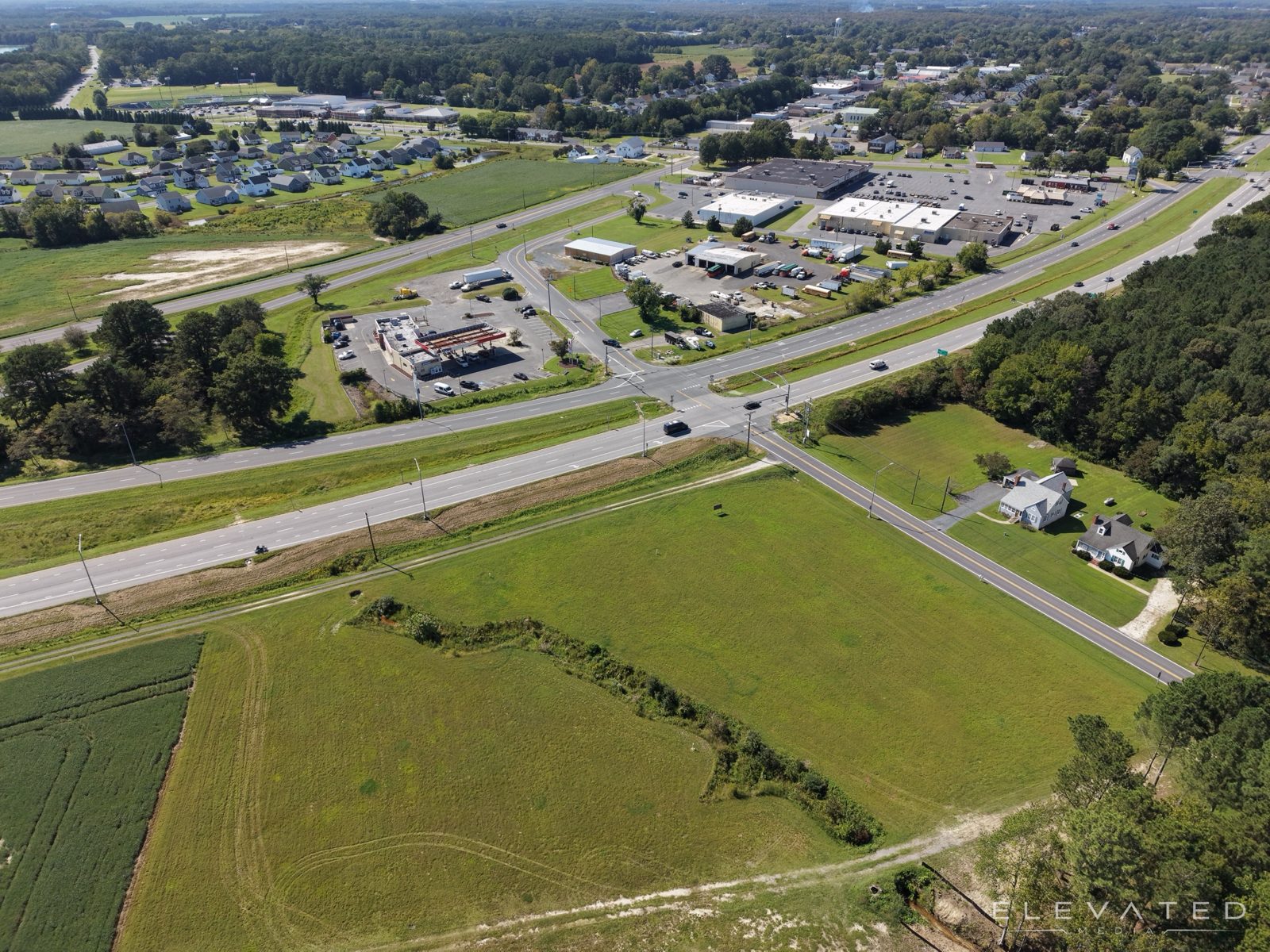 Open commercial land at a highway intersection across from a shopping center